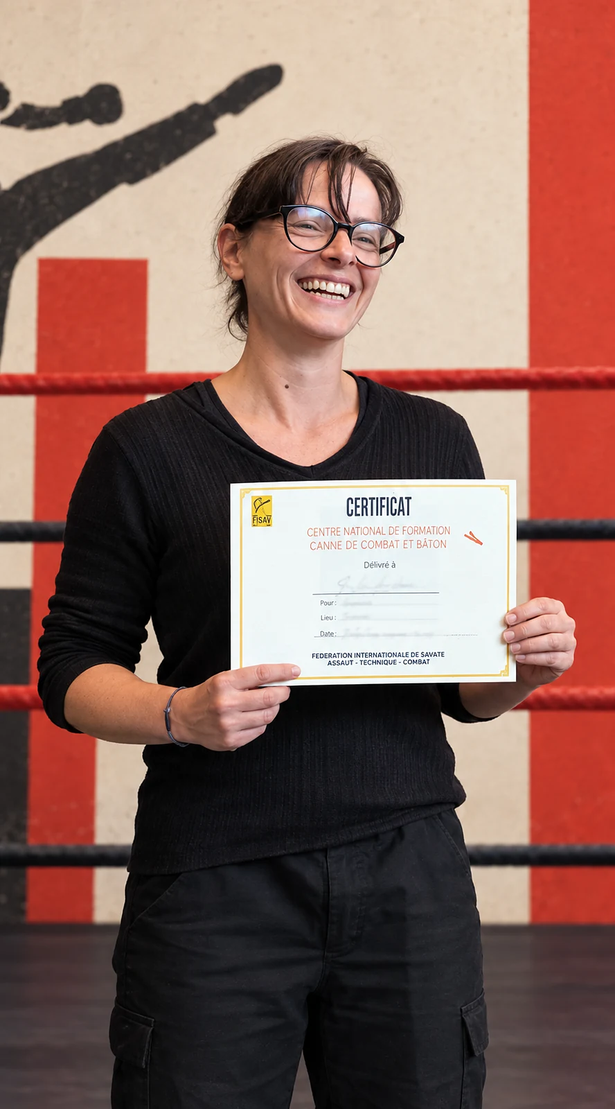 Anne Sophie, souriante, tenant un certificat, devant le ring.