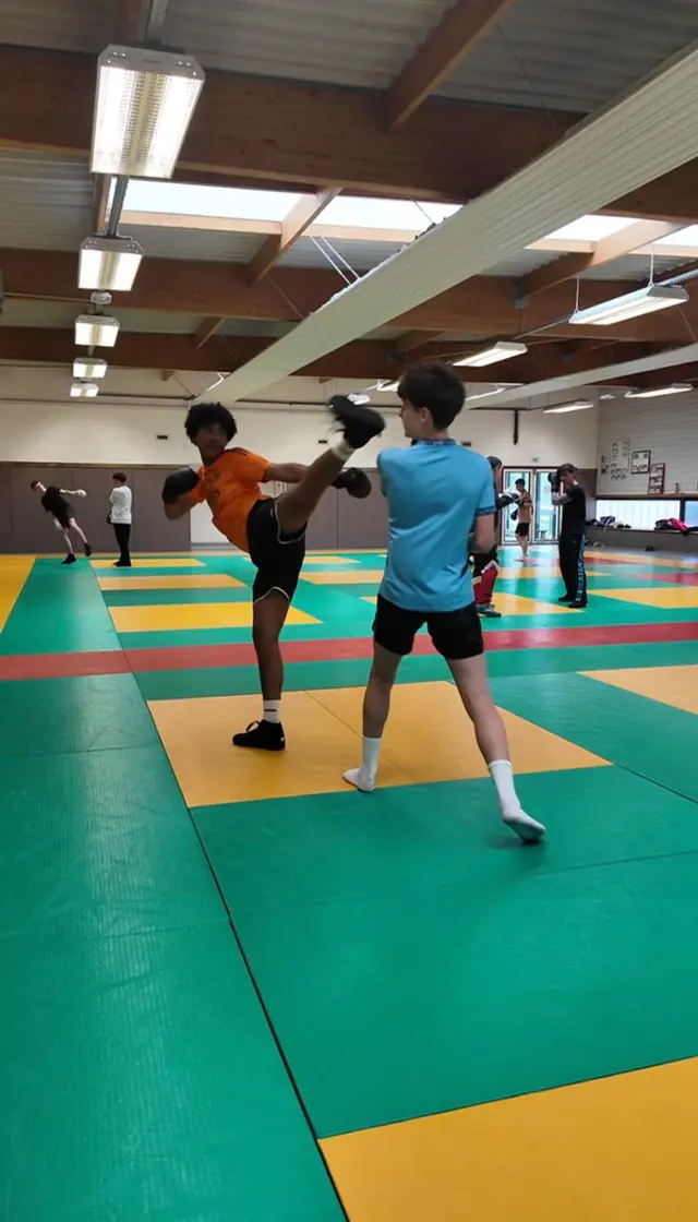 Coup de pied haut d’un boxeur en maillot orange.